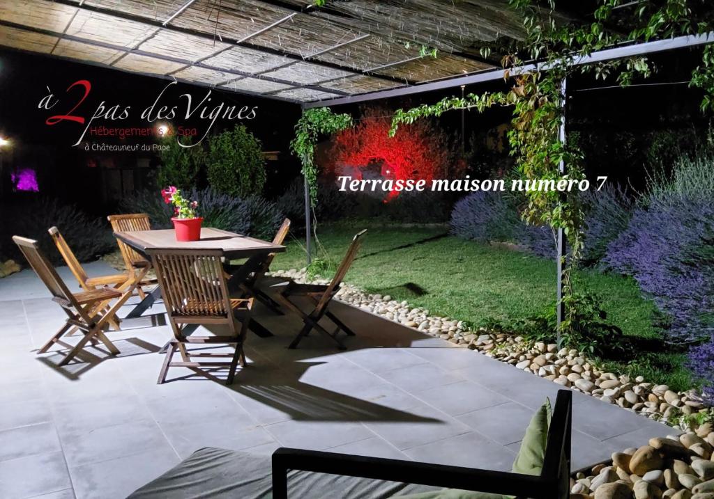 eine Terrasse mit einem Tisch und Stühlen im Garten in der Unterkunft Les Maisons et le Spa de à 2 pas des vignes à Châteauneuf du Pape in Châteauneuf-du-Pape