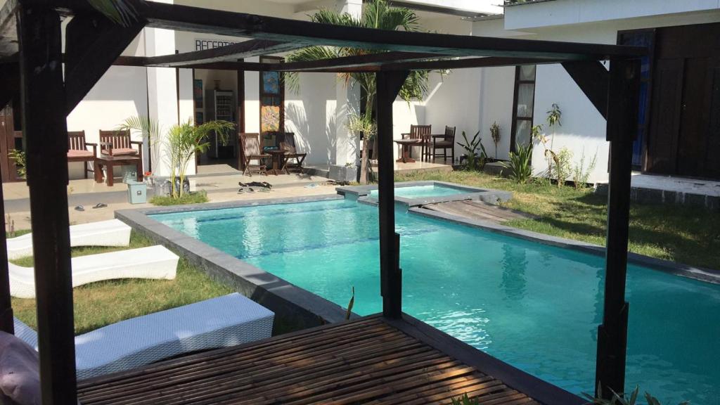 a swimming pool with a pergola next to a house at WHITE SANDS RESORT in Gili Trawangan