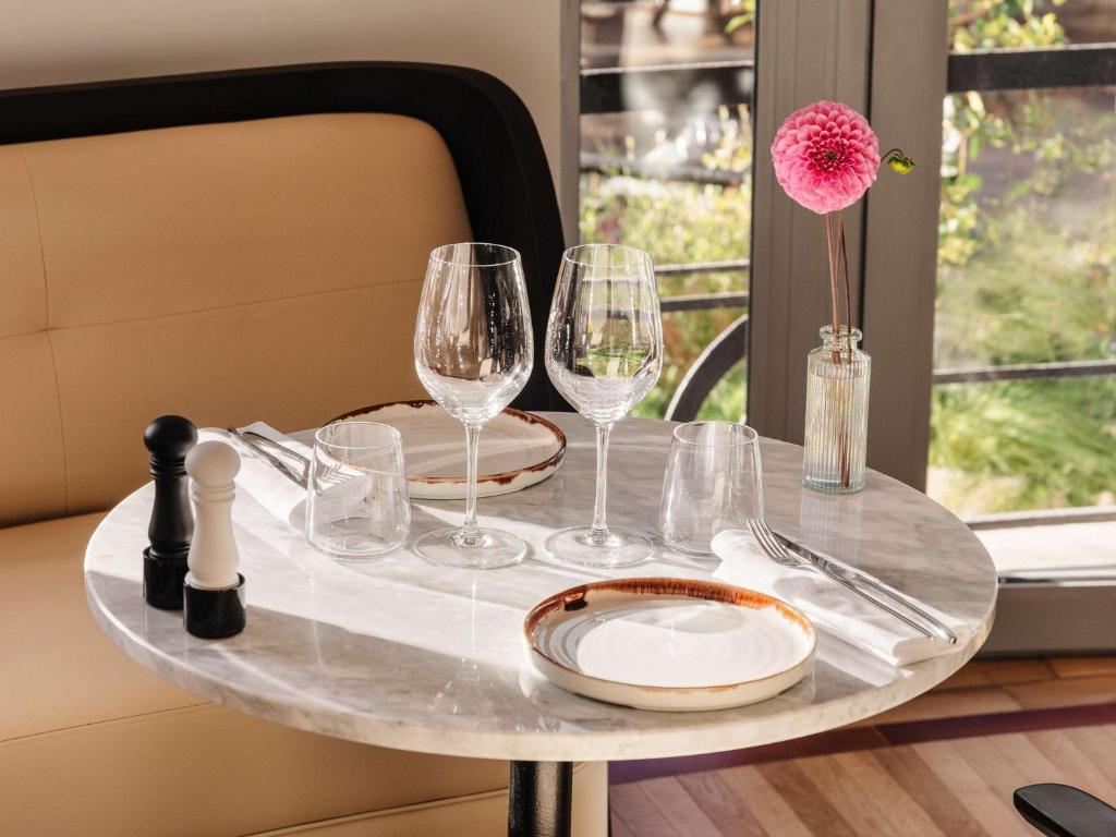a table with wine glasses and a flower on it at The 1932 Hotel & Spa Cap d'Antibes - MGallery Collection in Juan-les-Pins