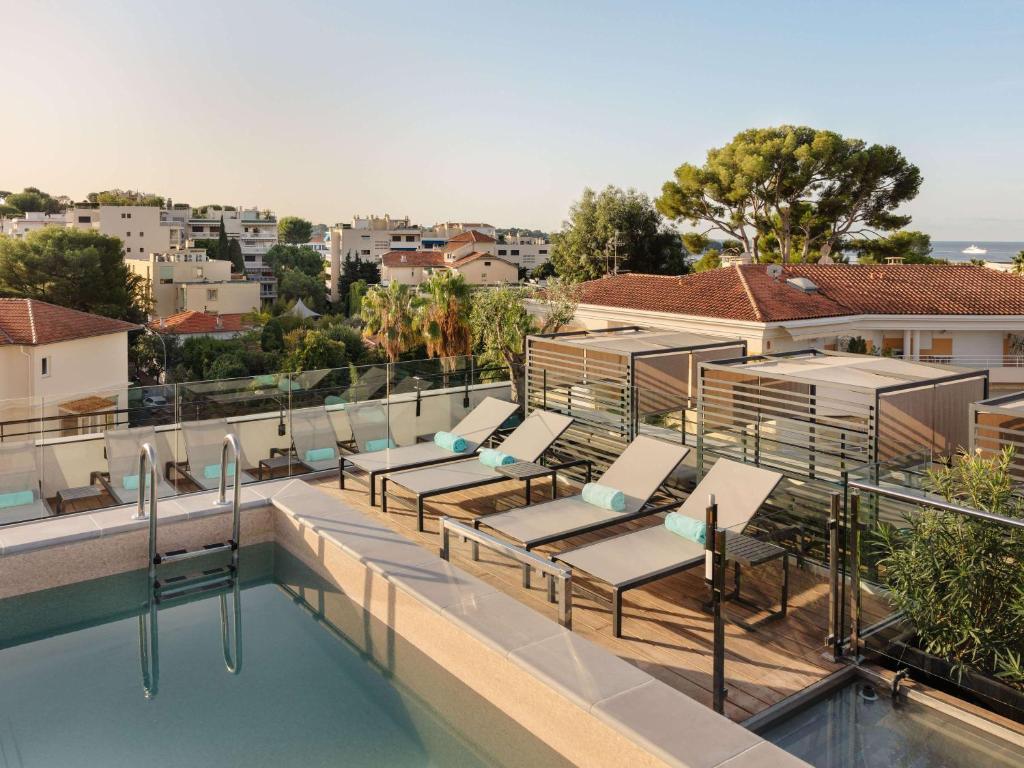 a swimming pool with lounge chairs on the roof of a building at The 1932 Hotel & Spa Cap d'Antibes - MGallery Collection in Juan-les-Pins