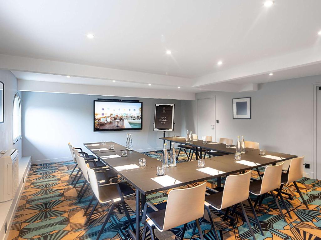 a conference room with tables and chairs and a flat screen tv at The 1932 Hotel & Spa Cap d'Antibes - MGallery Collection in Juan-les-Pins
