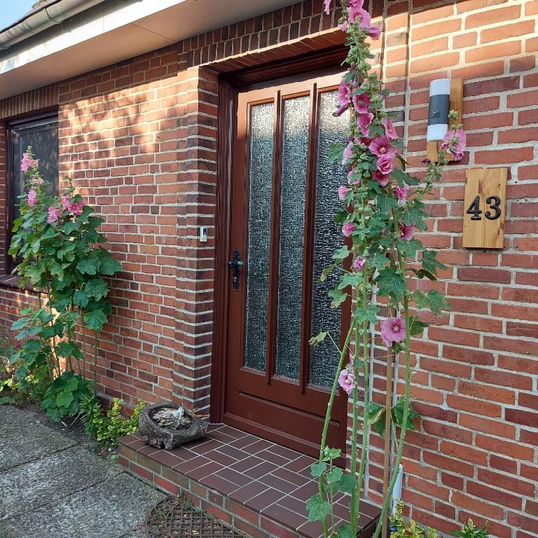 a front door of a brick house with pink flowers at Ferienhaus Hadler in Kaiser Wilhelm Koog