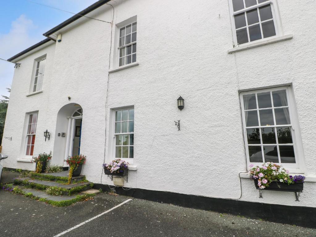 Una casa blanca con ventanas y flores en un estacionamiento. en Bay View Apartment, en Tenby