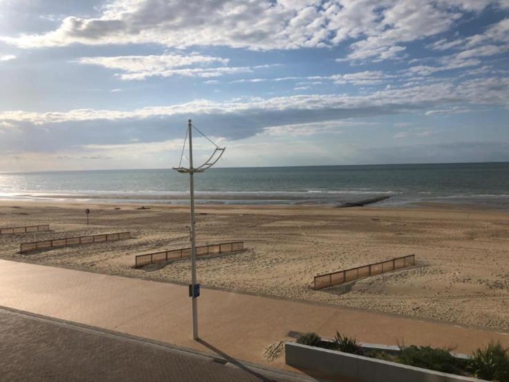 a beach with a light pole and the ocean at Appartement vue sur mer - Splendide localisation! in Sint-Idesbald