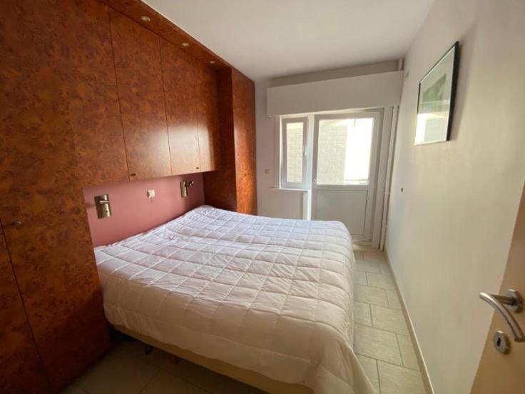 a bedroom with a large bed with a wooden headboard at Appartement vue sur mer - Splendide localisation! in Sint-Idesbald