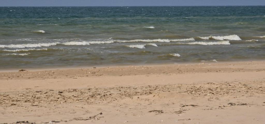 a sandy beach with waves in the ocean at Appartement vue sur mer - Splendide localisation! in Sint-Idesbald