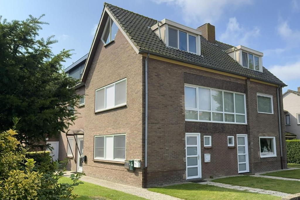 ein braunes Backsteinhaus mit weißen Fenstern in der Unterkunft Zeearend in Cadzand