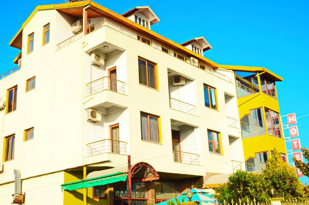 een wit gebouw met balkons in een straat bij Hotel Gjeli in Fier