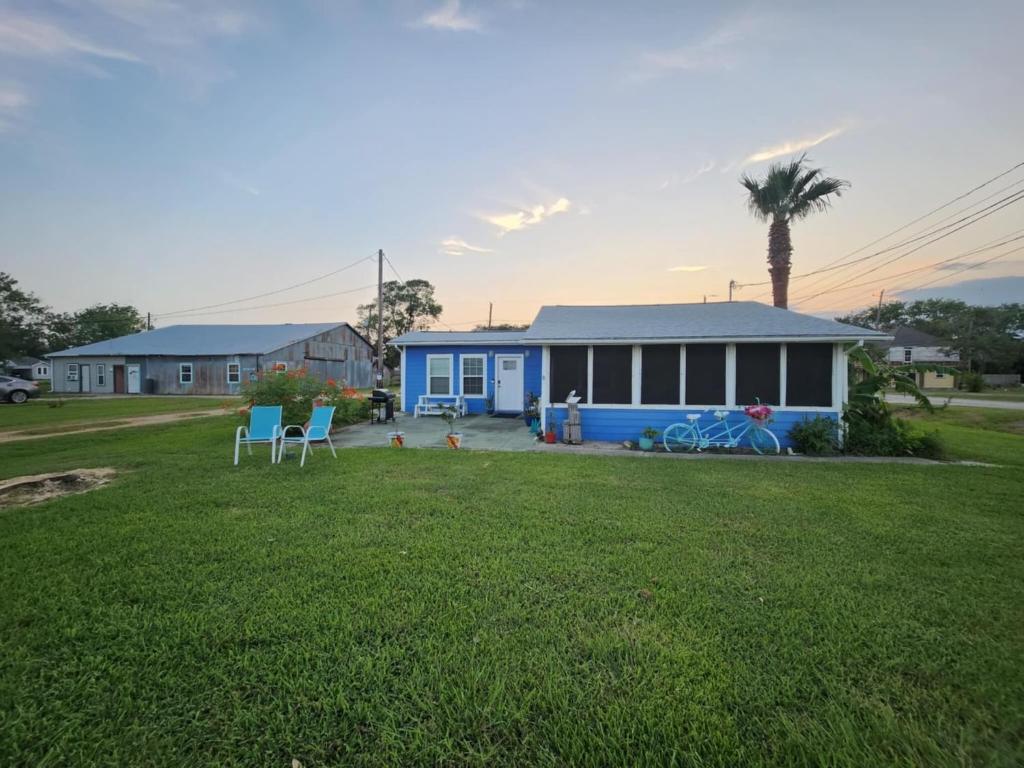 a blue house with two chairs in a yard at Coastal Cottage Bay House in Palacios