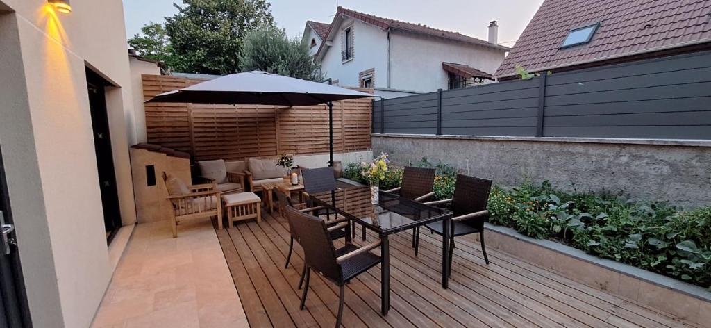 un patio avec une table, des chaises et un parasol dans l'établissement Maison Duplex - Proche de Paris, à Épinay-sur-Seine