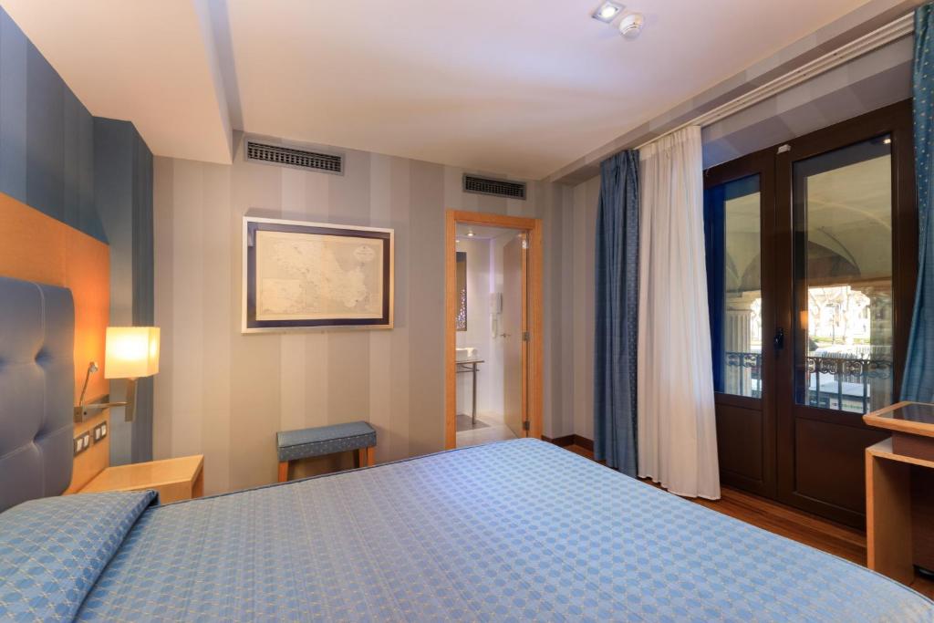 a bedroom with a blue bed and a window at Hotel del Mar in Barcelona