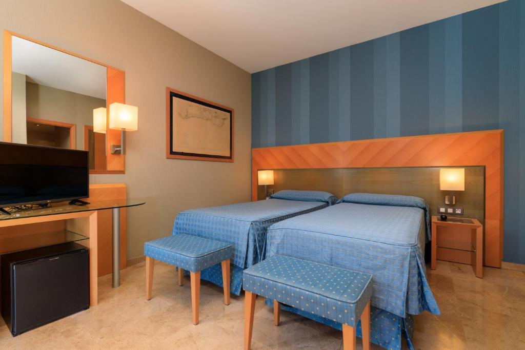 a bedroom with a bed and a desk and a television at Hotel del Mar in Barcelona
