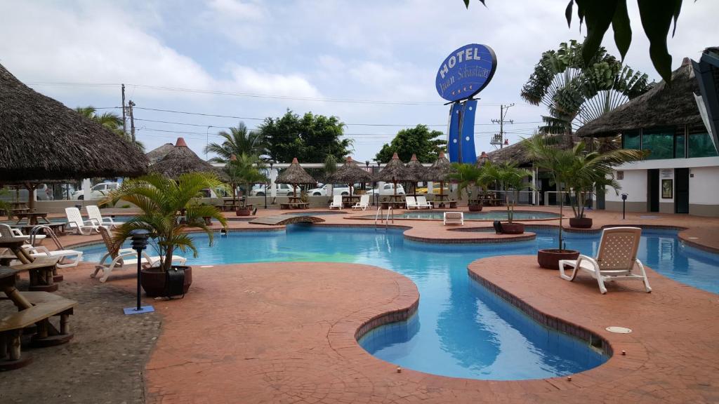 una piscina en un complejo con sillas y un cartel en Hotel Juan Sebastián, en Atacames