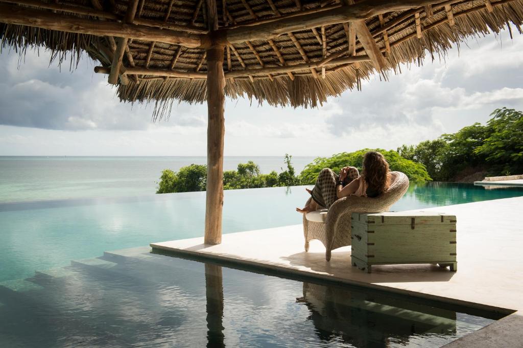 a woman sitting in a chair next to a swimming pool at Qambani Luxury Resort in Michamvi
