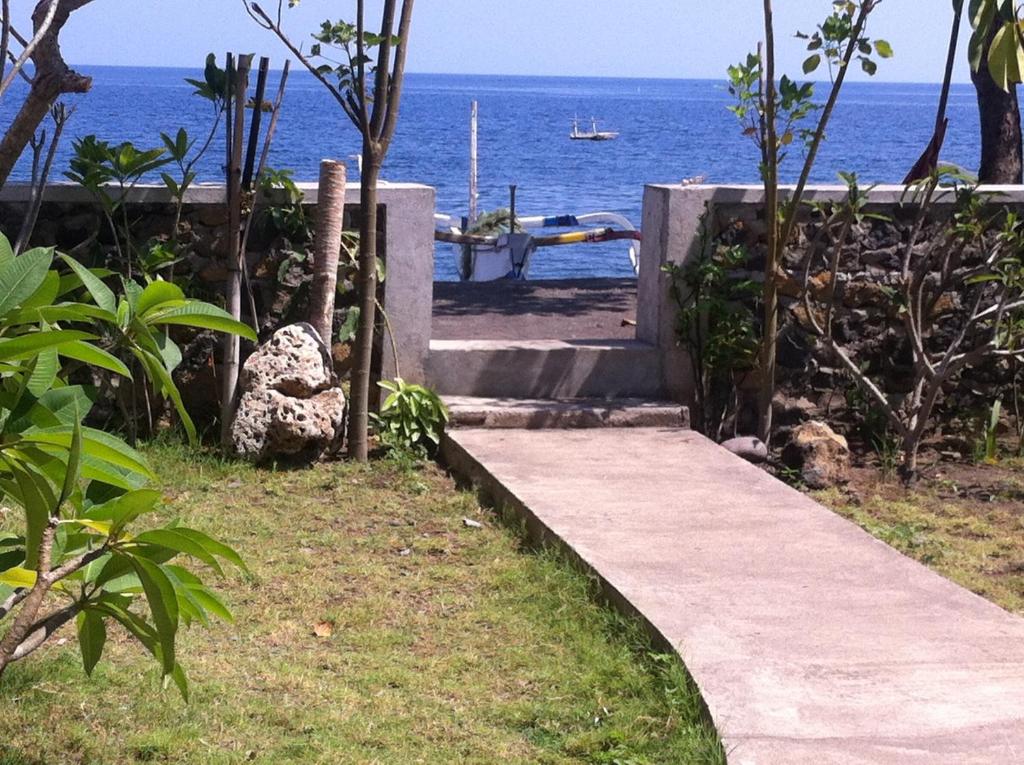 a path leading to the ocean with a boat in the water at Amed Sari Beach Guesthouse in Amed
