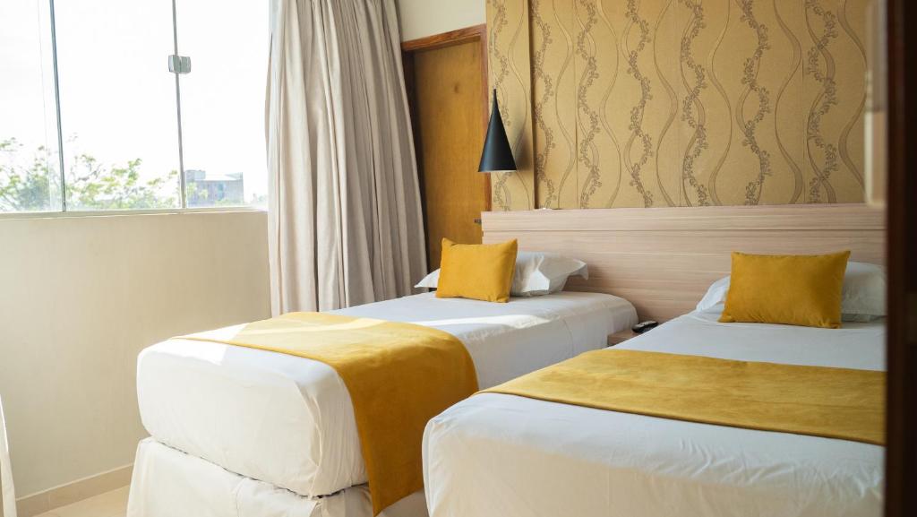um quarto de hotel com duas camas e uma janela em Mako´s Hotel em Encarnación