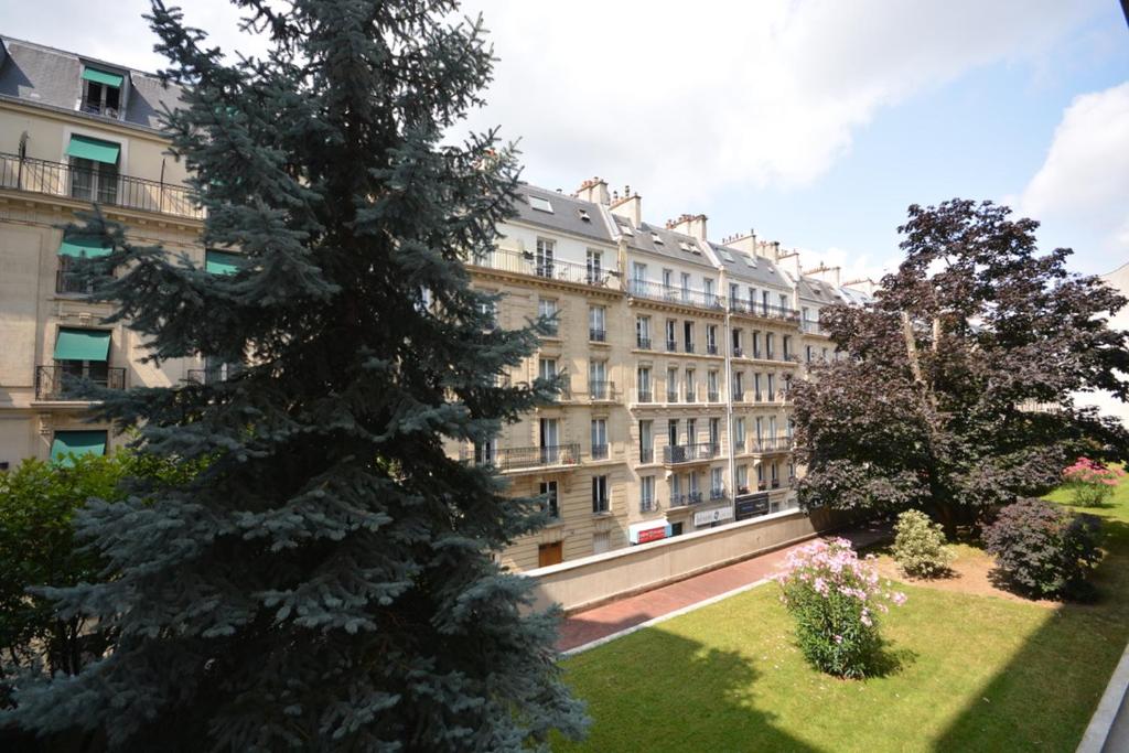 un grand arbre devant un grand bâtiment dans l'établissement Studio Trocadero - Sablons, à Paris