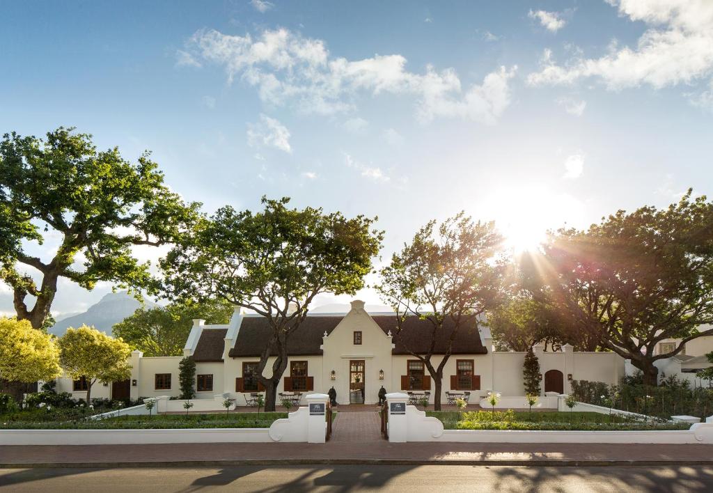 a large white house with the sun in the sky at Leeu House in Franschhoek
