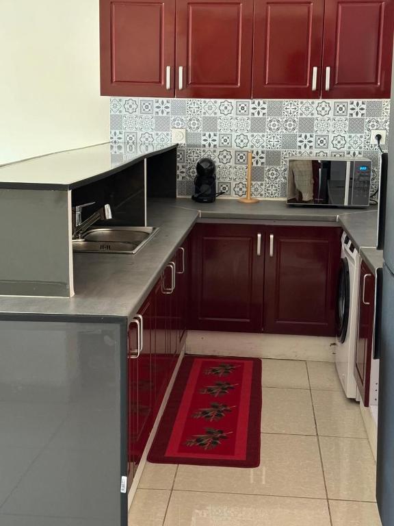 a kitchen with red cabinets and a red rug at Résidence la rosée in Mamoudzou
