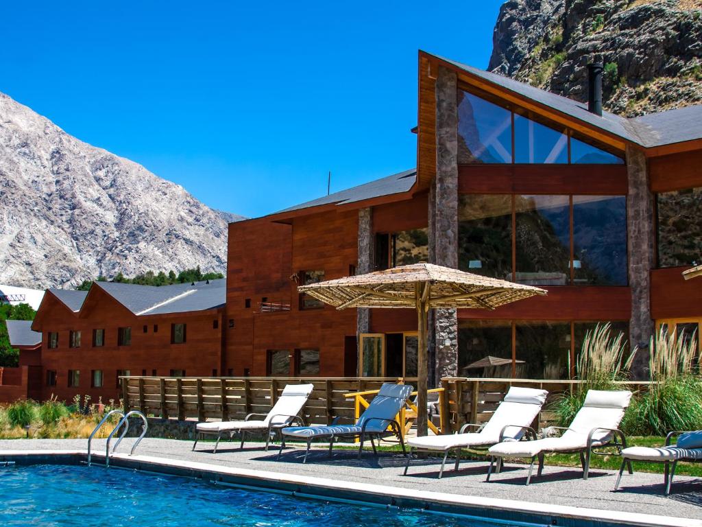 a resort with a pool and chairs and a building at NOI Puma Lodge in Machalí