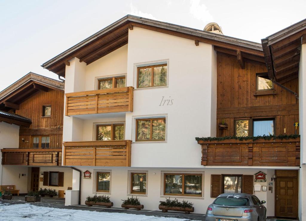 a house with wooden balconies and a car parked in front at Ciasa Iris in Colfosco