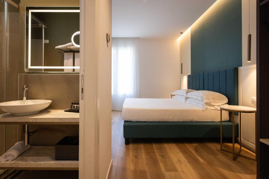 a bedroom with a bed and a sink and a mirror at Mondello Glam Hotel & Terrace in Mondello