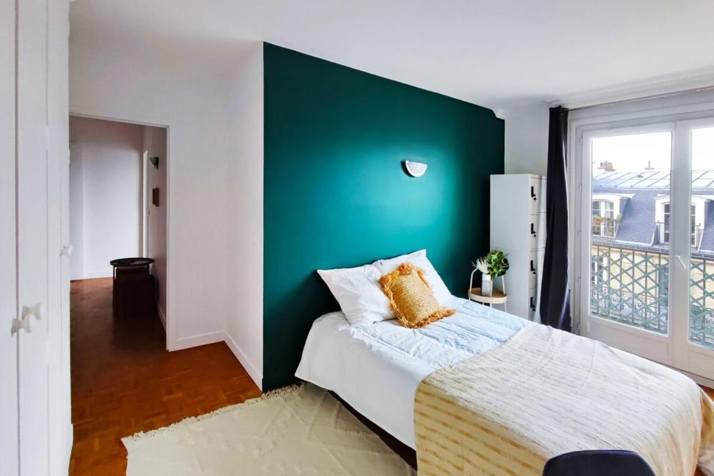 - une chambre avec un mur vert et un lit dans l'établissement Flexliving - room - Villon, à Paris