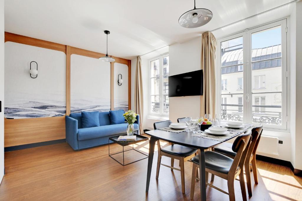 un salon avec une table et un canapé bleu dans l'établissement SERENERS - Charming Serviced Apartments - Bastille, à Paris