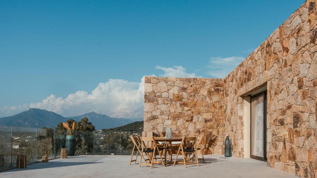une maison en pierre avec une table et des chaises sur une terrasse dans l'établissement Appartement premium de 70m2 avec piscine individuelle, à Grosseto-Prugna