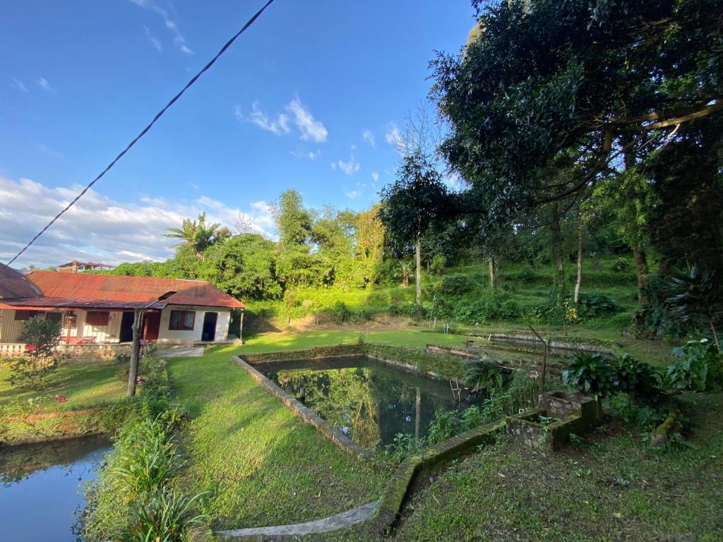 a garden with a pond in front of a house at Sibayak Multinational Rest House in Berastagi