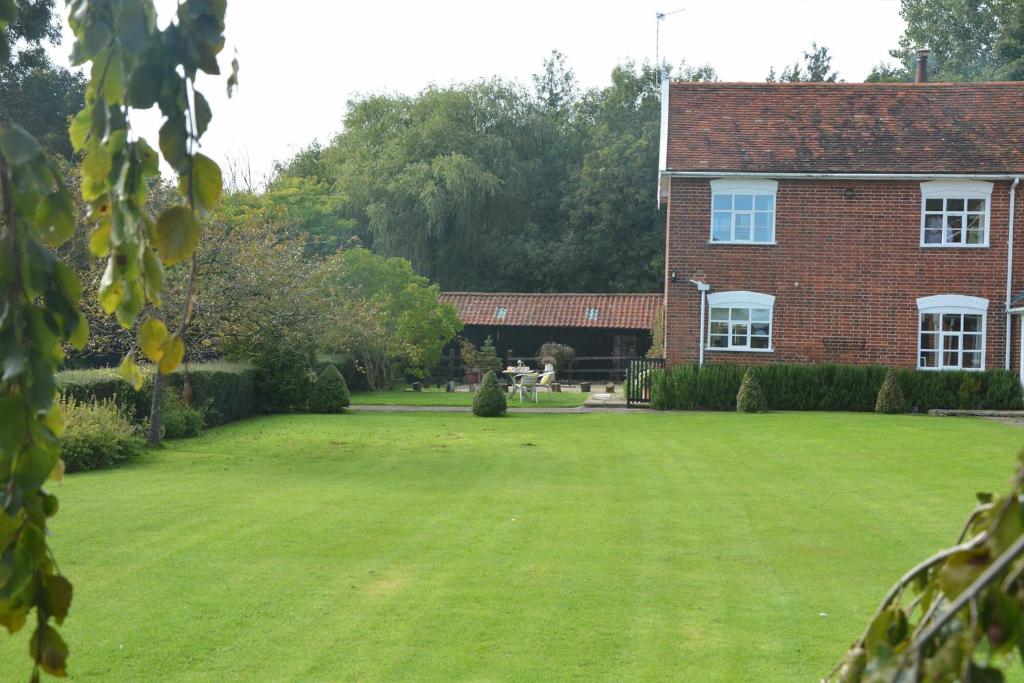 a large grassy yard in front of a brick house at Rookyards in Spexhall