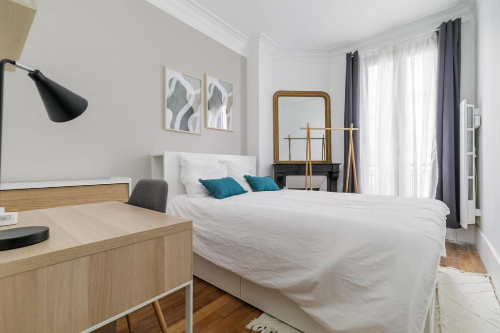 une chambre blanche avec un lit et un miroir dans l'établissement Flexliving - room - Caulaincourt, à Paris