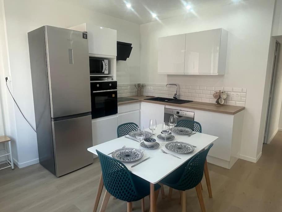 une cuisine avec une table avec des chaises et un réfrigérateur dans l'établissement Maison de pêcheur à Rosendaël, à Dunkerque