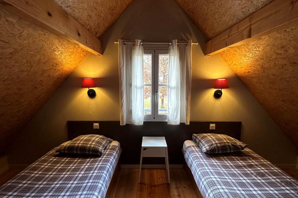 Dos camas en una habitación con ventana. en Les chalets d'Arrens, en Arrens-Marsous