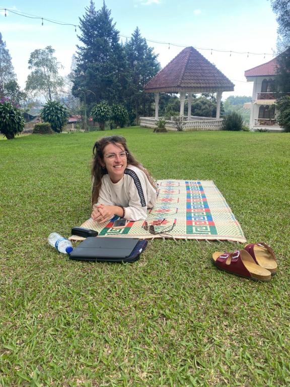 a young girl laying on the grass with a laptop at Sibayak Multinational Rest House in Berastagi