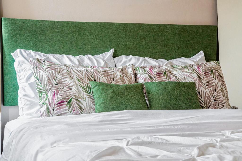 a bed with white sheets and green headboard and pillows at Casa Palma in La Paz