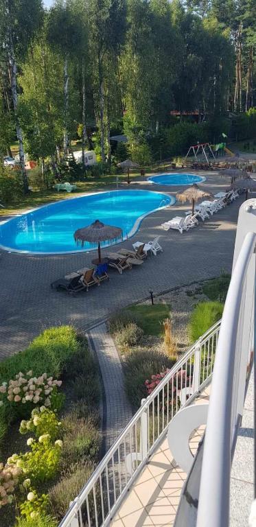 a view of a pool with umbrellas and chairs at Romantyczny Apartament HAPPY 16 BASEN & KORT TENISOWY, OCHRONA 24 h - dla maksymalnie 6 osób in Pobierowo