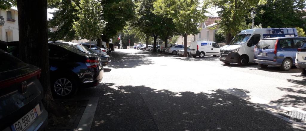 une rue avec des voitures garées sur le bord de la route dans l'établissement Chez René, à Montagnac