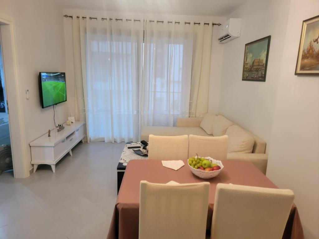 a living room with a table and chairs and a television at Henri's Apartments Vlore in Vlorë