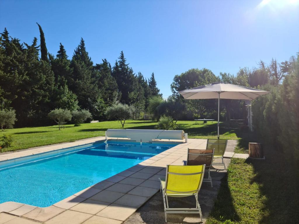 une piscine avec des chaises et un parasol dans l'établissement Vacances, à Sénas