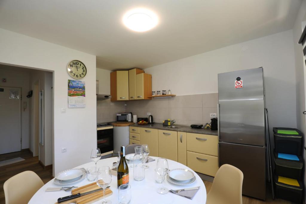 a kitchen with a table with wine glasses and a refrigerator at Apartment Ondina in Rijeka