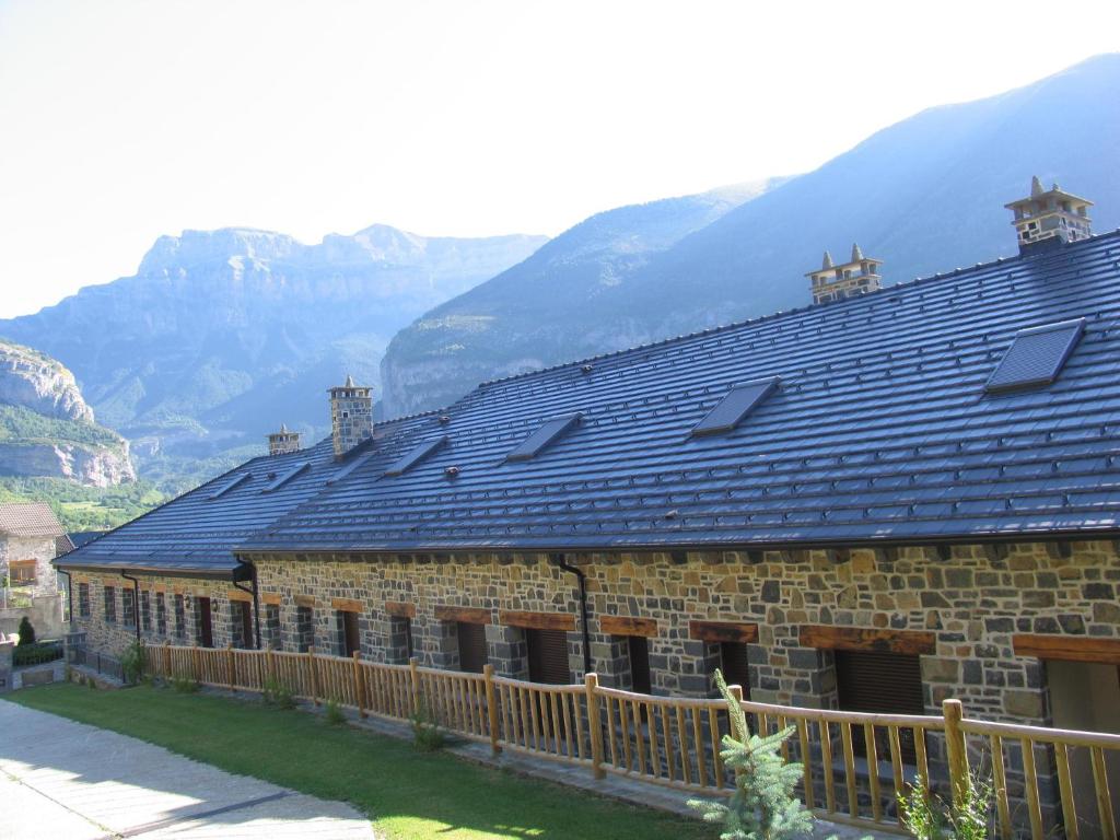 a large brick building with mountains in the background at Apartamentos Russell in Torla-Ordesa