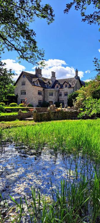 a large house with a pond in front of it at The Loft at Goytre Hall in Abergavenny