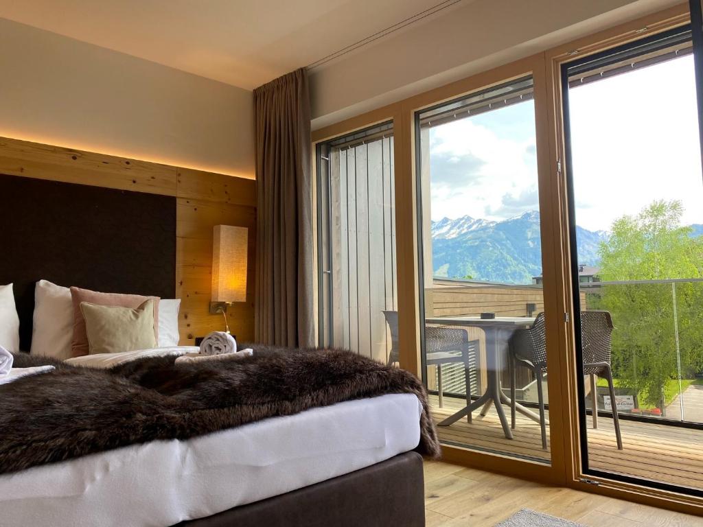 a bedroom with a bed and a balcony with a table at Spa Apartments - next to AreitXpress Liftstation in Zell am See