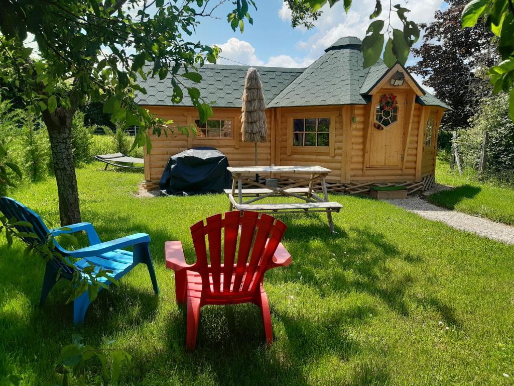a group of chairs in the grass in front of a cabin at Cabane Kota finlandais in Laives