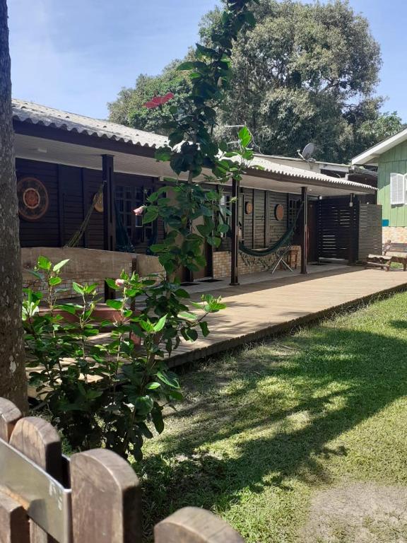 a house with a wooden porch with a fence at Pousada Lua Cheia in Ilha do Mel