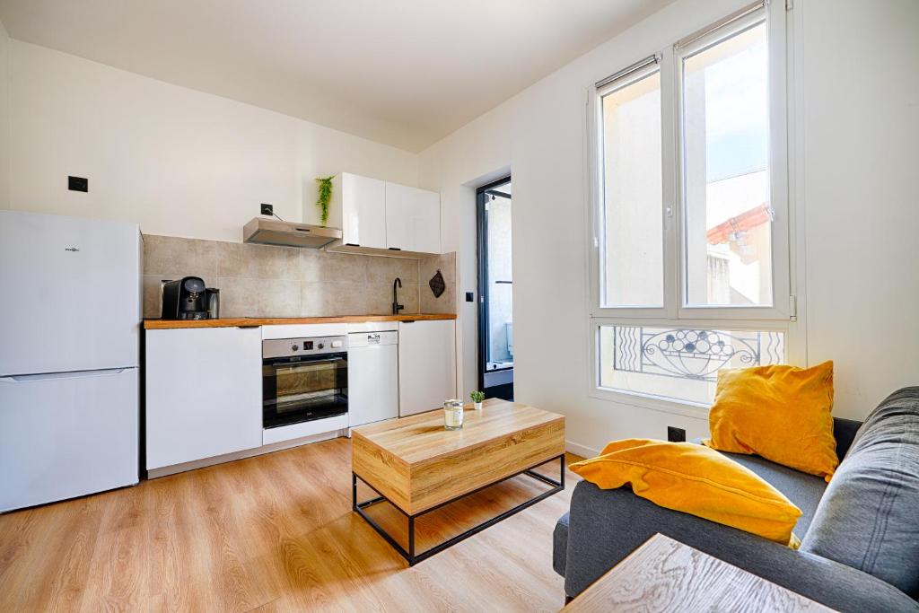 eine Küche und ein Wohnzimmer mit einer Couch und einem Tisch in der Unterkunft Le Cœur des Antiquaires - 5 min de Paris in Saint-Ouen