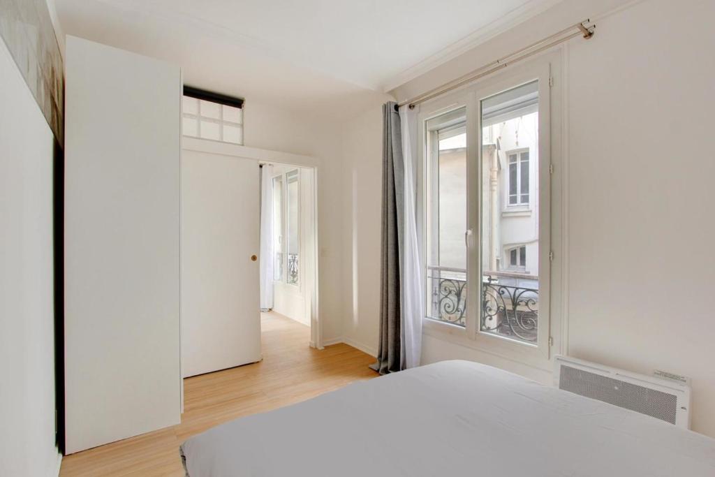 une chambre avec un lit blanc et une fenêtre dans l'établissement Flex Living - whole house - Claude Bernard, à Paris