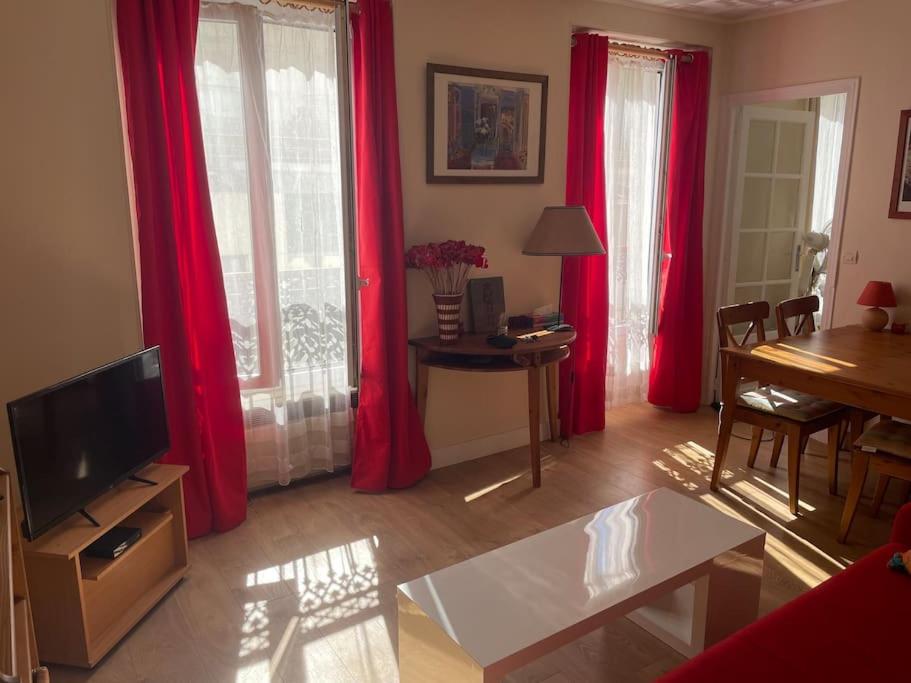 - un salon avec des rideaux rouges et une télévision dans l'établissement Coquelicot du Canal Saint-Martin, à Paris