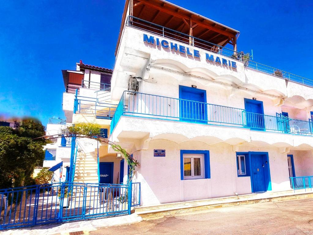 a white building with blue windows and a balcony at Michele Marie apts in Agia Pelagia